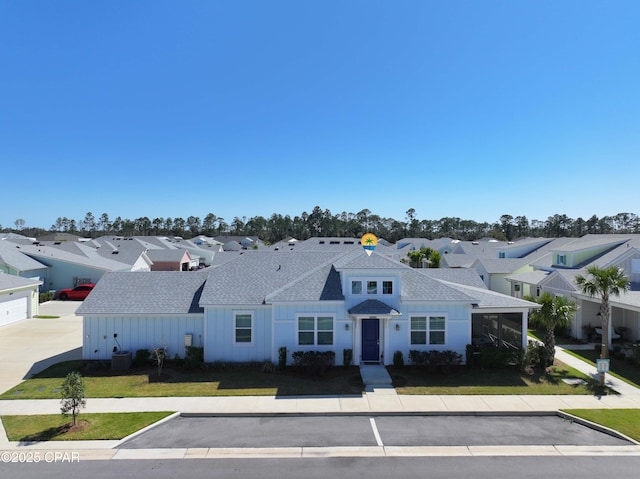 view of front facade featuring a residential view, a front yard, and a shingled roof