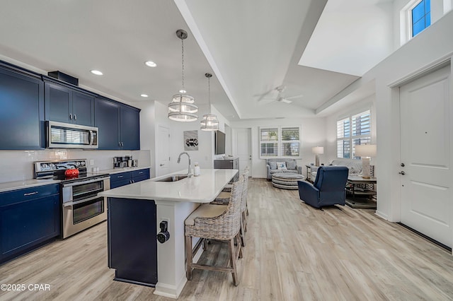 kitchen with open floor plan, light countertops, appliances with stainless steel finishes, blue cabinets, and a sink