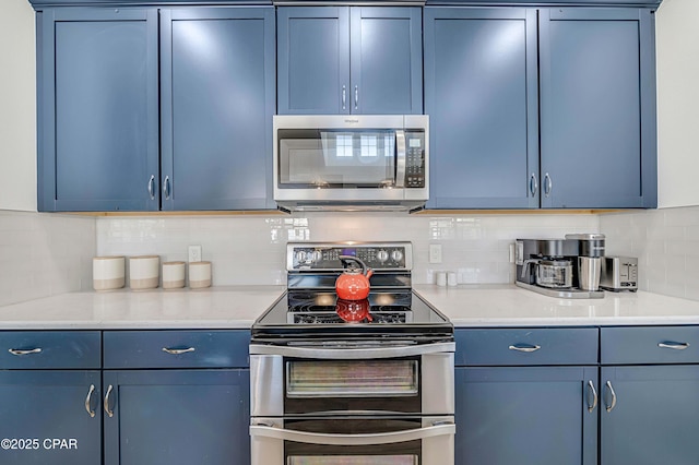 kitchen with blue cabinets, stainless steel appliances, and decorative backsplash