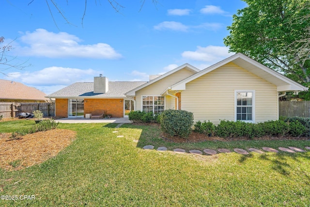 back of property with a patio area, a lawn, a chimney, and fence