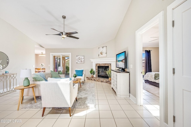 living room with a glass covered fireplace, vaulted ceiling, light tile patterned floors, and ceiling fan