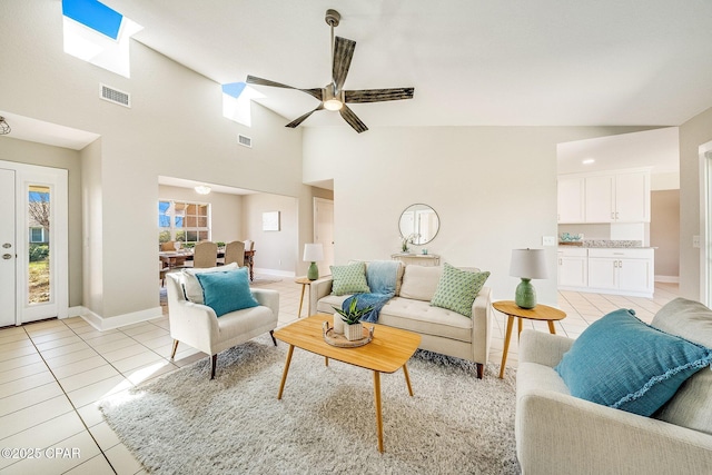 living area featuring light tile patterned floors, visible vents, baseboards, and ceiling fan