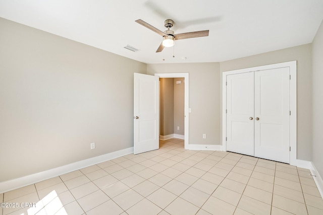 unfurnished bedroom featuring visible vents, a closet, light tile patterned floors, baseboards, and ceiling fan