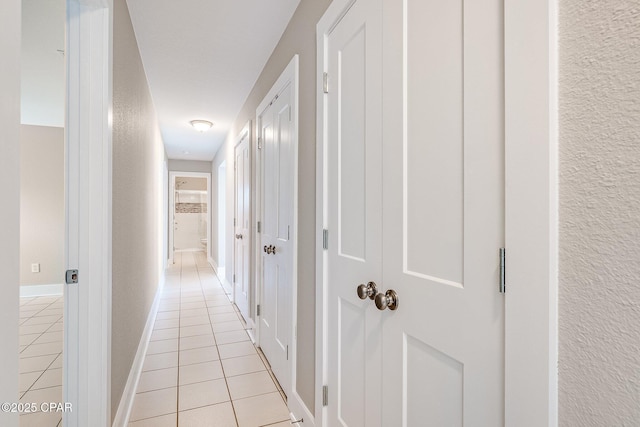 corridor featuring light tile patterned floors and baseboards