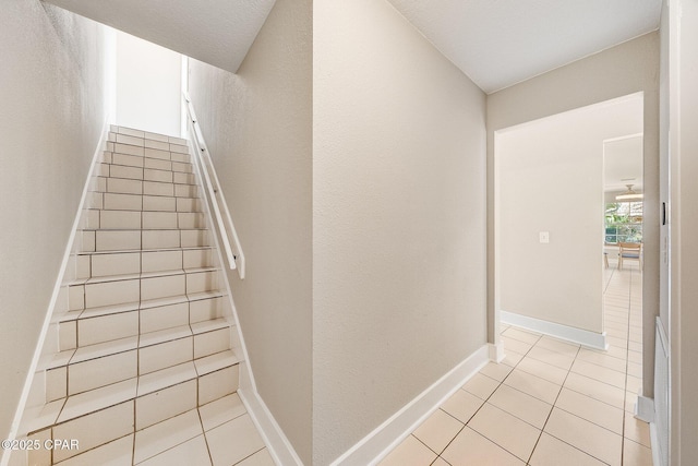 stairway with tile patterned floors and baseboards