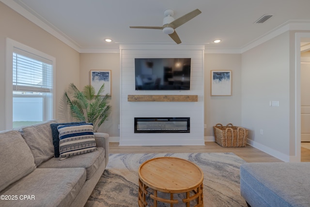 living room featuring a large fireplace, wood finished floors, visible vents, and ornamental molding