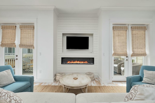 living area featuring crown molding, a large fireplace, wood finished floors, and baseboards