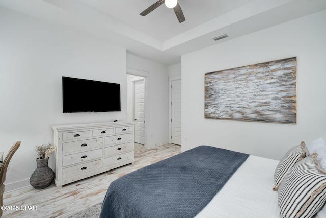 bedroom featuring baseboards, visible vents, ceiling fan, and a tray ceiling