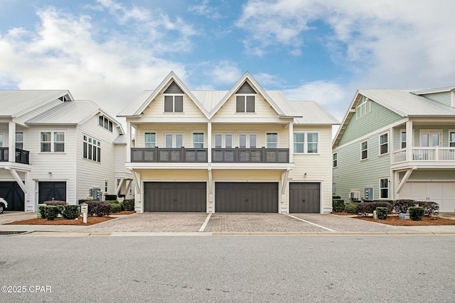 view of front of property with driveway, metal roof, a balcony, and a garage