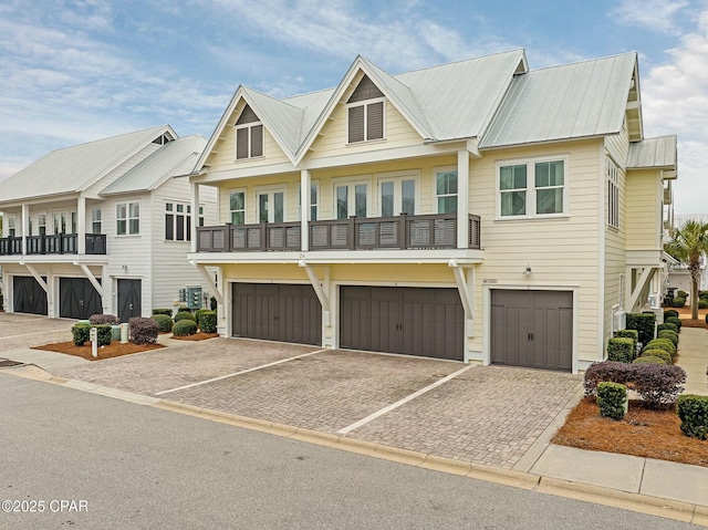 view of front of property featuring metal roof, driveway, a garage, and a balcony