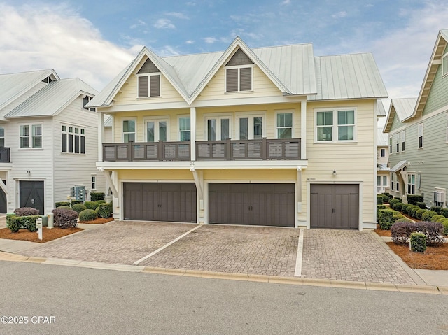 view of front of property featuring a balcony, driveway, metal roof, and an attached garage