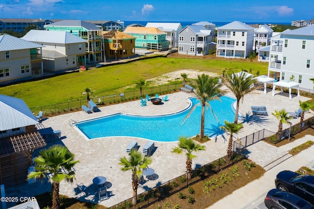 community pool with fence, a patio area, and a residential view