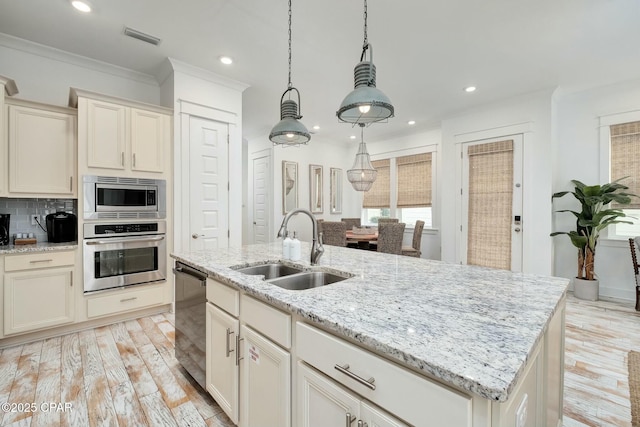 kitchen with a sink, appliances with stainless steel finishes, visible vents, light wood-type flooring, and ornamental molding