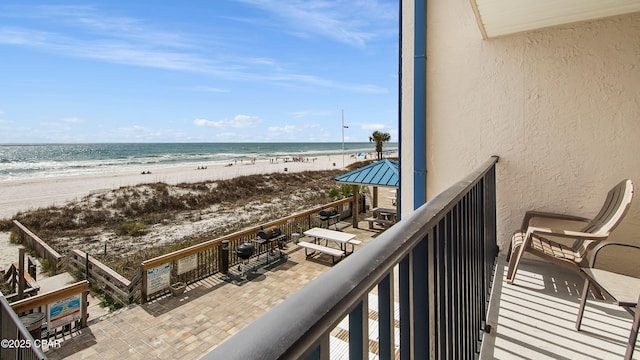 balcony featuring a view of the beach and a water view