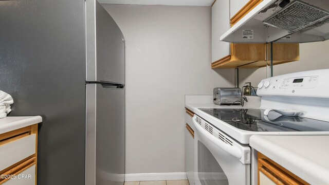 kitchen with under cabinet range hood, a toaster, light countertops, freestanding refrigerator, and electric stove