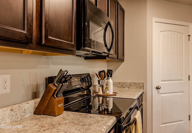 kitchen featuring black appliances, light stone counters, and dark brown cabinets