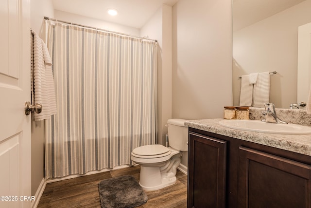 bathroom with baseboards, toilet, a shower with shower curtain, wood finished floors, and vanity