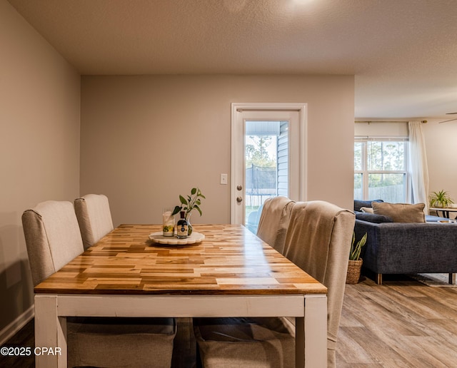 dining area with a textured ceiling, a healthy amount of sunlight, and wood finished floors