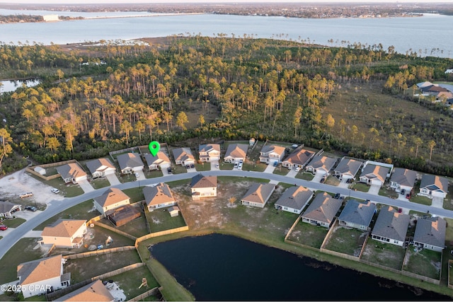 drone / aerial view featuring a residential view, a wooded view, and a water view