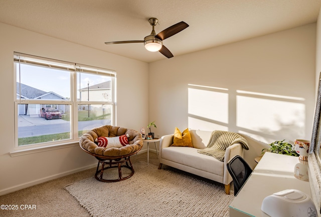 living area featuring a ceiling fan, carpet, and baseboards