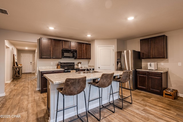 kitchen featuring visible vents, dark brown cabinetry, black appliances, and light wood-style flooring