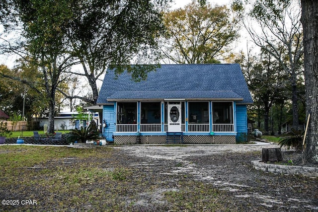 view of front of house featuring a sunroom and a shingled roof