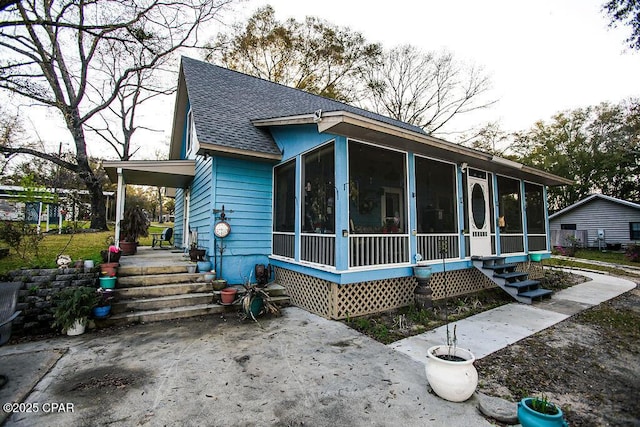 exterior space with a sunroom and a shingled roof