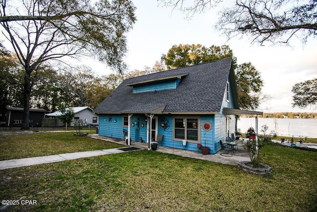 view of front of home featuring a patio area, roof with shingles, a front yard, and fence