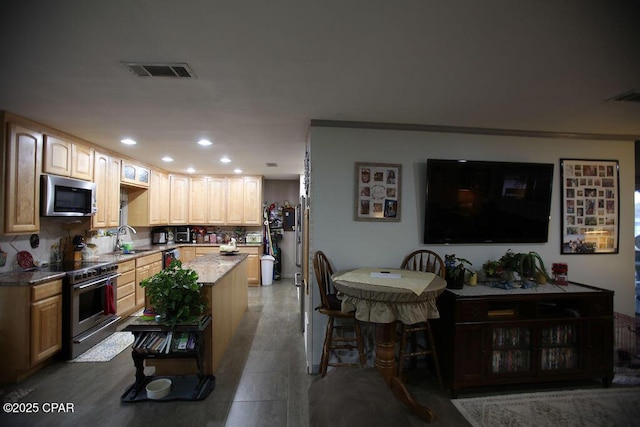 kitchen featuring a sink, visible vents, a kitchen island, and appliances with stainless steel finishes