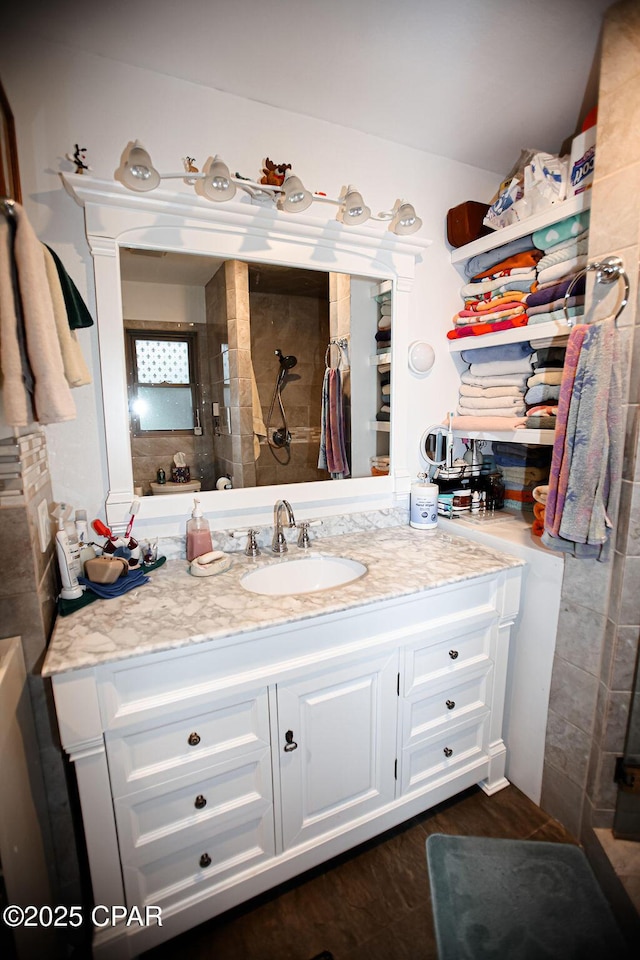 bathroom with a tile shower, vanity, and wood finished floors