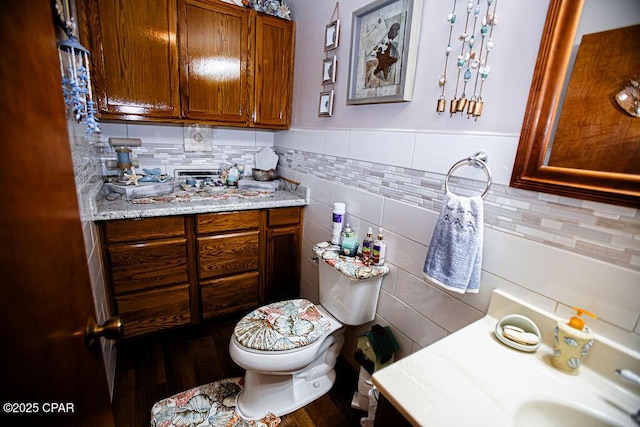 bathroom featuring a sink, toilet, tile walls, and wood finished floors