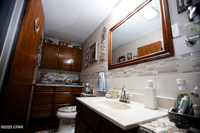 bathroom featuring vanity, tile walls, toilet, and tasteful backsplash