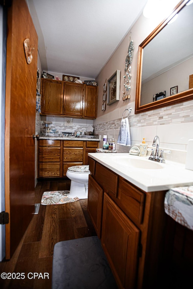 bathroom featuring toilet, tile walls, wood finished floors, and vanity