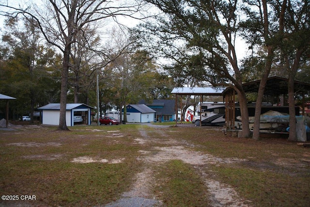 view of yard with a carport, driveway, and an outdoor structure