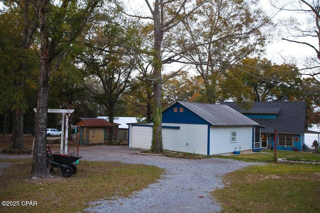 view of side of property featuring a storage shed, a yard, a garage, an outdoor structure, and driveway