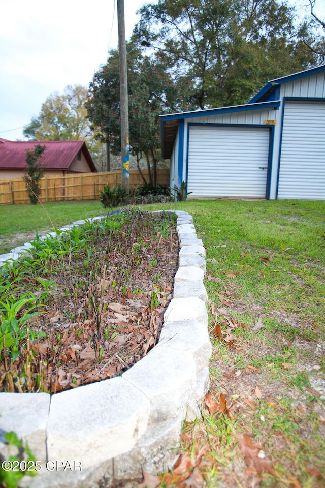 view of yard featuring an outbuilding, fence, and a garage