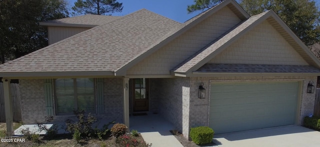 view of front of property featuring concrete driveway, an attached garage, and roof with shingles