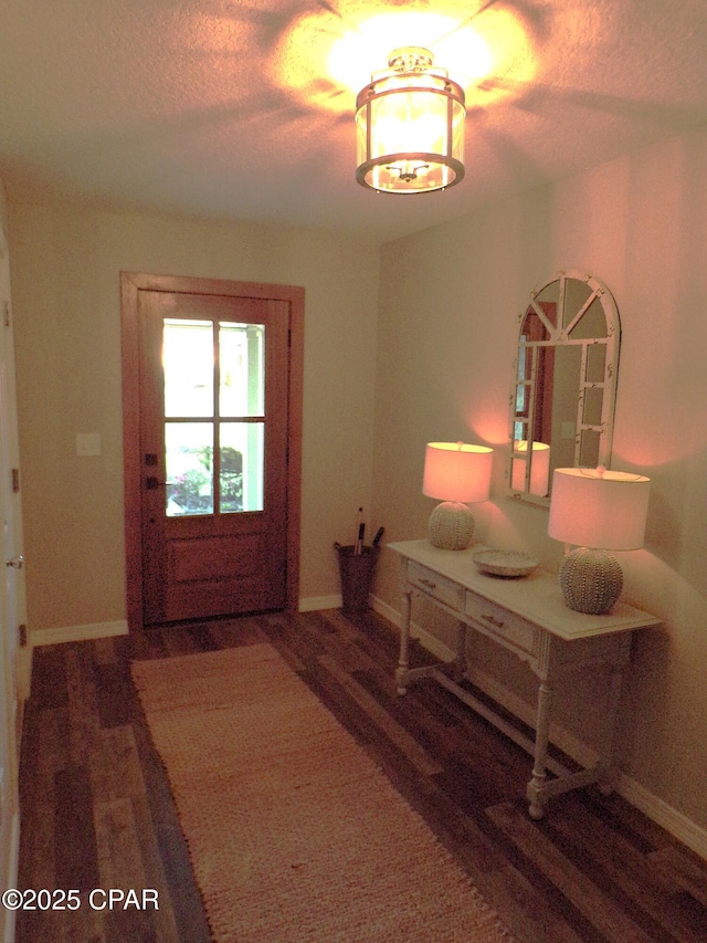 foyer entrance featuring wood finished floors, baseboards, and a textured ceiling