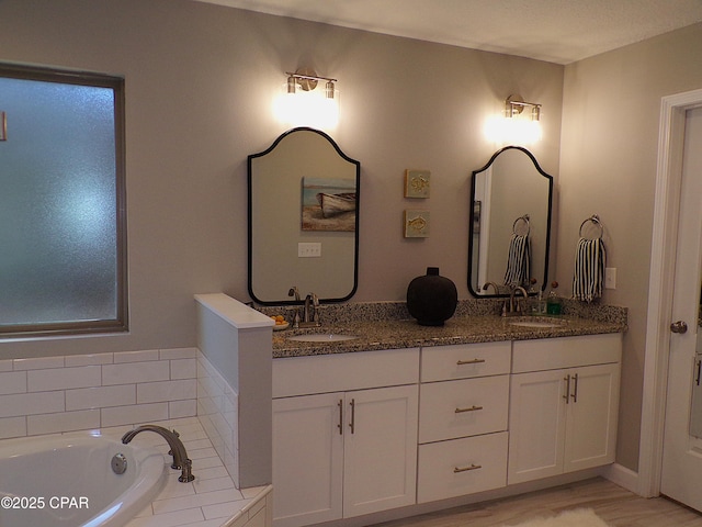 full bath featuring double vanity, a relaxing tiled tub, and a sink