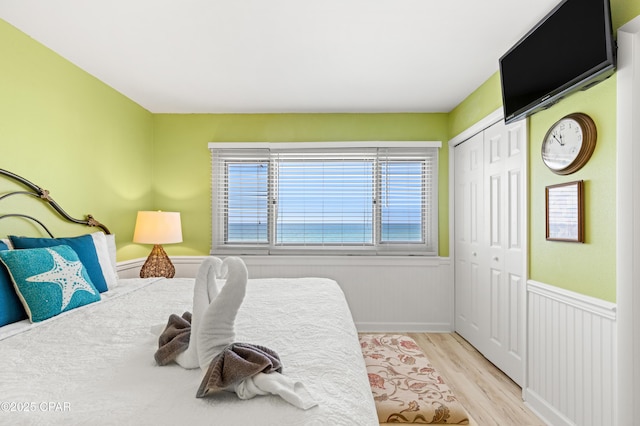 bedroom with wood finished floors, a closet, and wainscoting