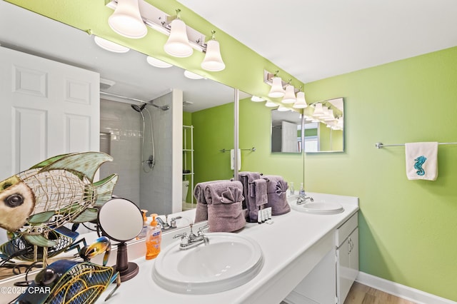 bathroom featuring a sink, tiled shower, and double vanity