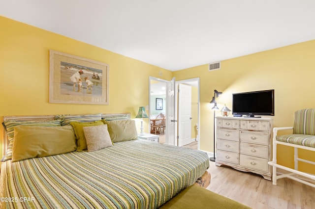 bedroom with visible vents, light wood-type flooring, and baseboards