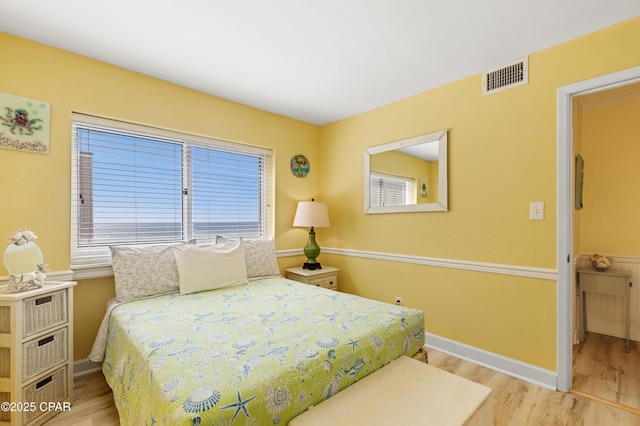 bedroom with visible vents, baseboards, and wood finished floors