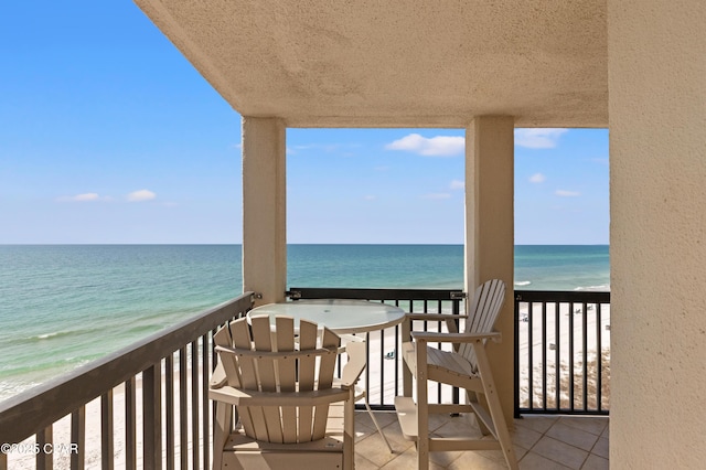 balcony featuring a view of the beach and a water view