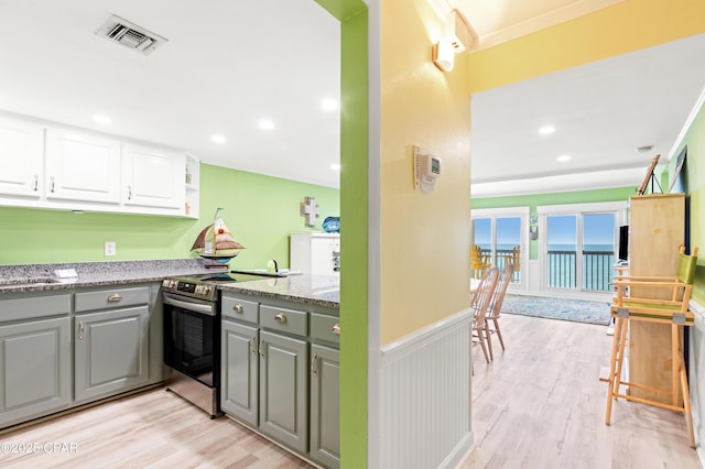 kitchen with visible vents, electric range, gray cabinets, light wood-style floors, and wainscoting