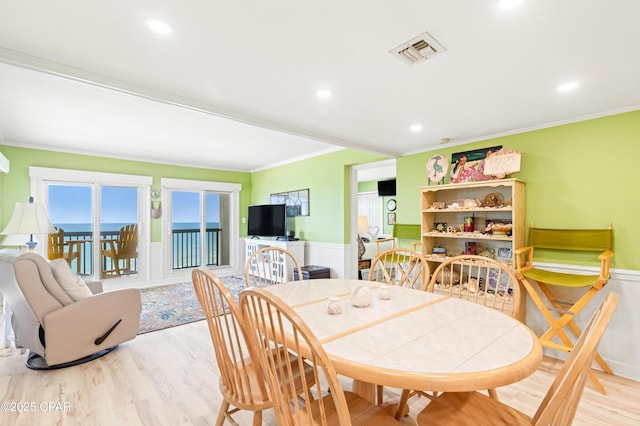 dining area with visible vents, a wainscoted wall, and ornamental molding