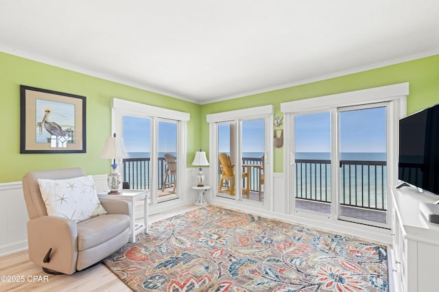 interior space featuring light wood finished floors, wainscoting, and crown molding