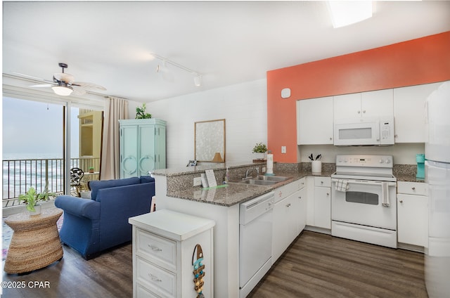 kitchen featuring dark wood-type flooring, open floor plan, a peninsula, white cabinets, and white appliances
