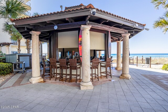 view of patio featuring a view of the beach, a water view, and outdoor dry bar