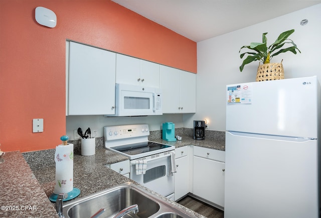 kitchen with white appliances, dark countertops, wood finished floors, and white cabinetry